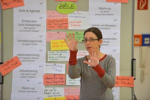 Eine Frau zeigt beim Präsentieren beide Hände.