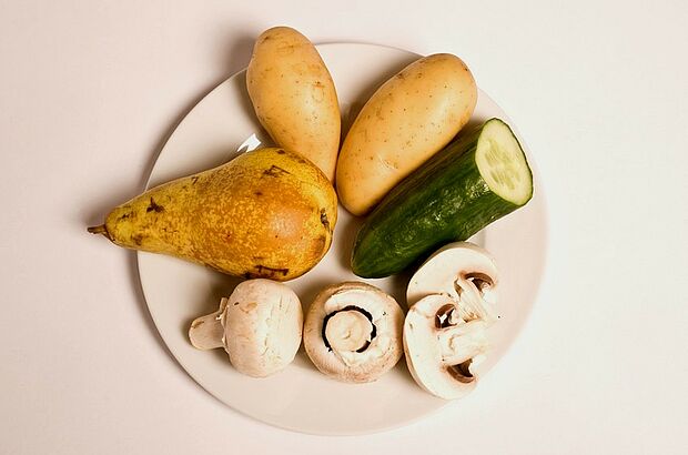 Birne, Pilze, Kartoffel und Gurke auf einem Teller