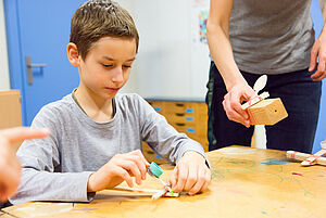 Ein Junge probiert einen selbst gebastelten Katapult aus.