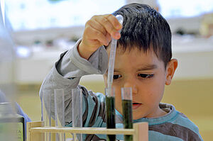 Ein Junge pipettiert Wasser aus einem Reagenzglas.