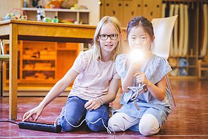 Kinder leuchten mit Taschenlampe in die Kamera