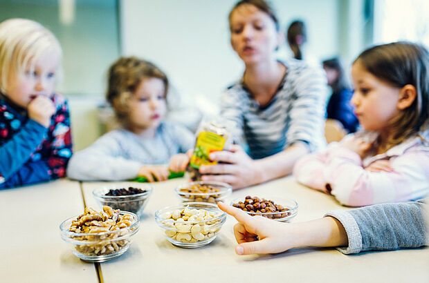 Kinder an einem Tisch auf dem sortierte Nüsse stehen.