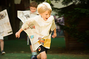 Ein Junge rennt. Eine Zeitungsseite haftet dabei an seinem Körper.