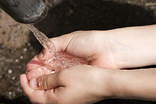 Kinderhände unter Wasserquelle