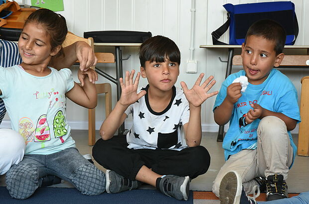 Kinder machen verschiedene Bewegungen mit Händen und Mund