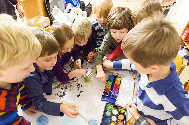 Mehrere Kinder malen gemeinsam mit Wasserfarben