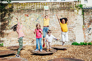 Kinder springen auf dem Spielplatz mit der Zertifizierungsplakette