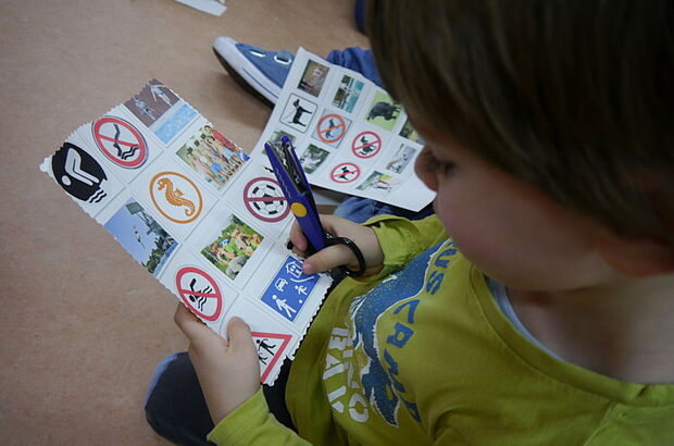 Ein Kind sieht sich verschiedene Piktogramme an.