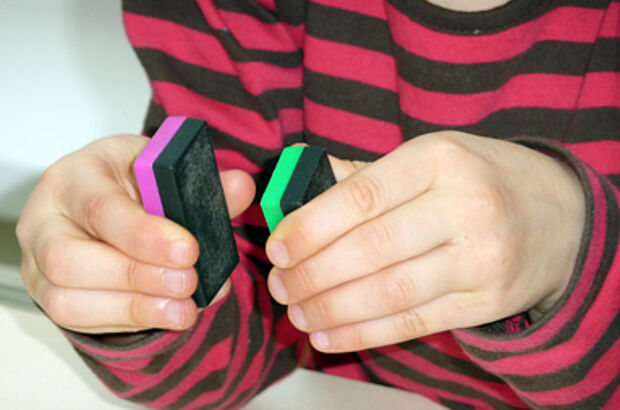 Ein Kind versucht zwei gleichgepolte Magnete aneinander zu halten.