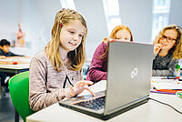 Drei Mädchen schreiben etwas an einem Laptop