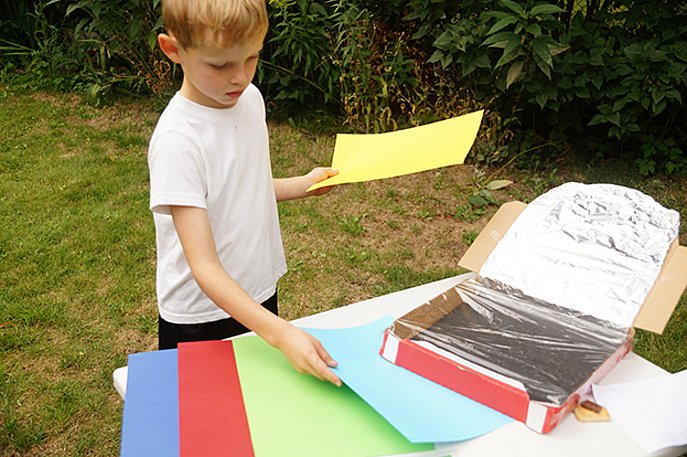 Ein Junge überlegt, welches farbige Papier er in seinen Solarofen stecken könnte