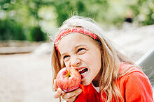 Mädchen beißt in einen Apfel