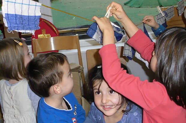 Kinder hängen Stofftücher an eine Wäscheleine