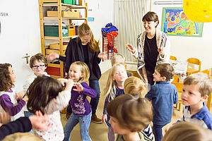 Kinder und Erzieher tanzen in einem Raum