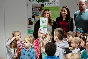 Eine Zertifizierungs-Plakette inmitten einer Traube von Kindern.