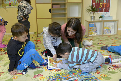 Eine Frau schaut zusammen mit Kindern ein Buch an