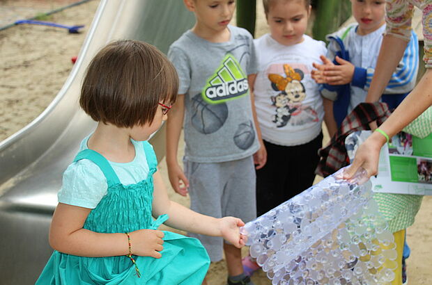 Kinder nehmen eine Gummimatte in die Hand.