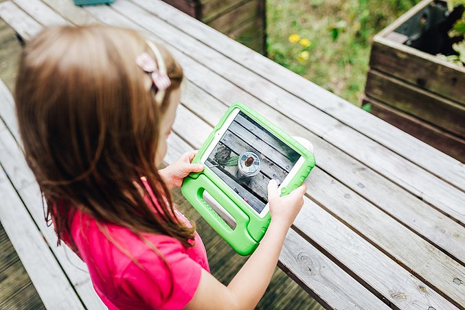 Kind mit Tablet fotografiert eine Kastanie