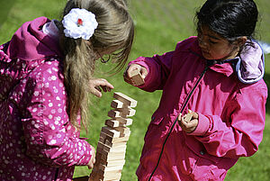 Zwei Mädchen stapeln Holzbausteine zum Turm auf