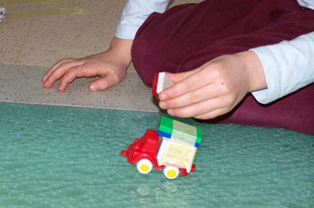 Ein Spielzeugauto wird fortbewegt, indem ihm ein Magnet aufgeklebt wurde und es mit einem weiteren abgestoßen wird.