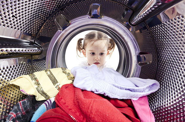 Ein Mädchen schaut in das Innere einer Waschmaschine