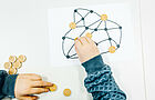 Kinderhände verteilen Holzspielsteine auf einem Netzwerkbild