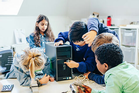 Fünf Kinder untersuchen gemeinsam ein Computer-Terminal