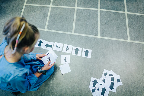 Ein Mädchen von oben fotografiert, das Karten mit Pfeilen sortiert