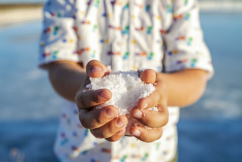 Kind hält Meersalz in den Händen.