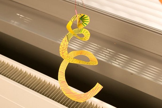 Gelbe Papierspirale hängt über einem Heizungskörper