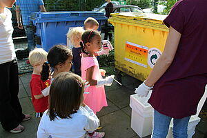 Kitakinder erkunden die Mülltrennung an Mülltonnen