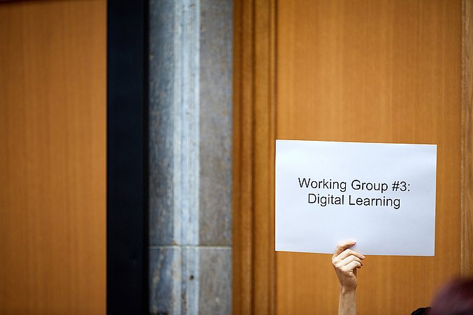 A white sign with the words "Working Group #3 Digital Learning"