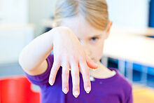 Ein Mädchen zeigt seine nasse Hand.
