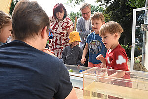 Senatorin Astrid-Sabine Busse und Kinder stehen um Behälter mit Wasser und beobachten, was passiert